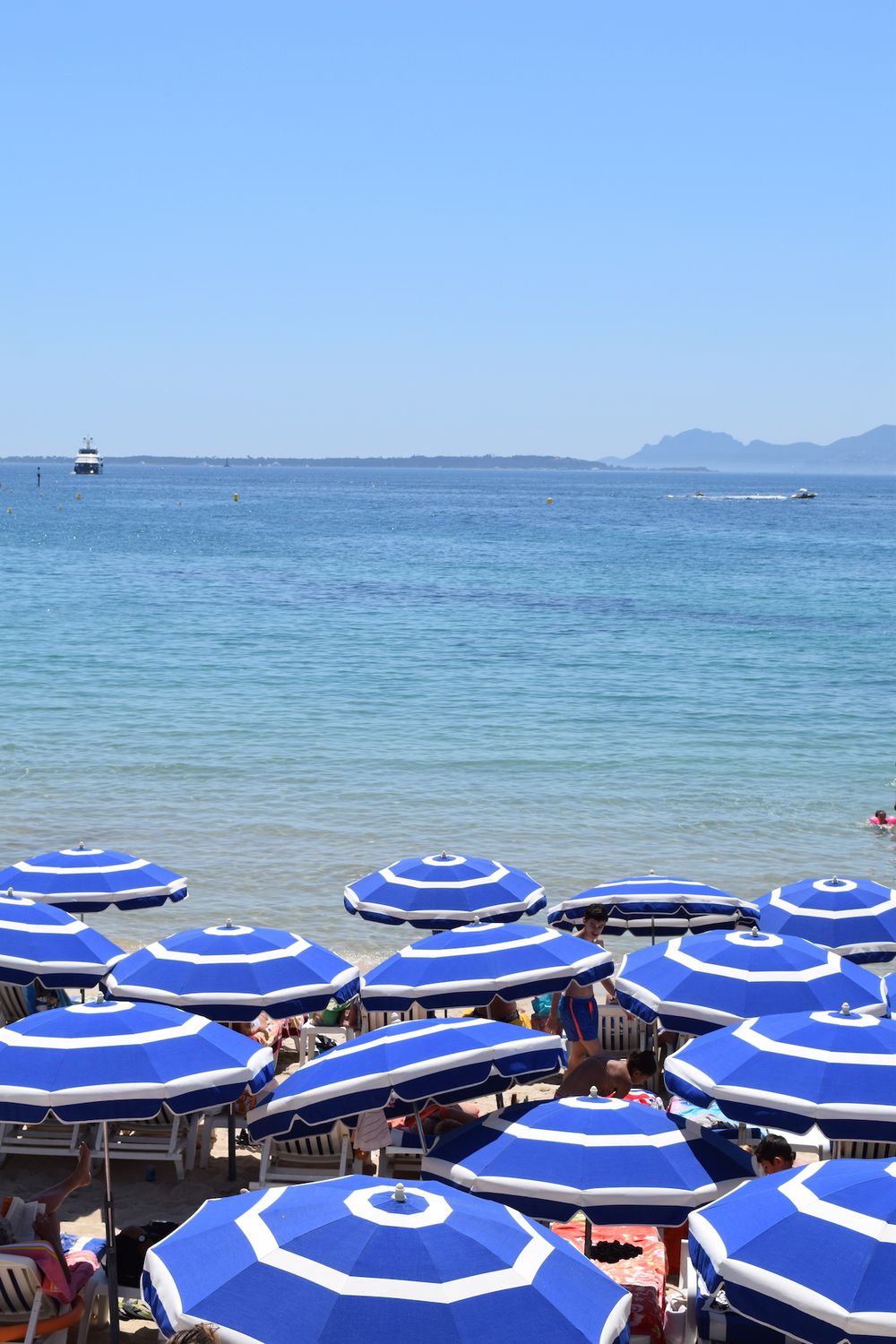 Blue and white umbrellas on beach by Juan-Les-Pins, France